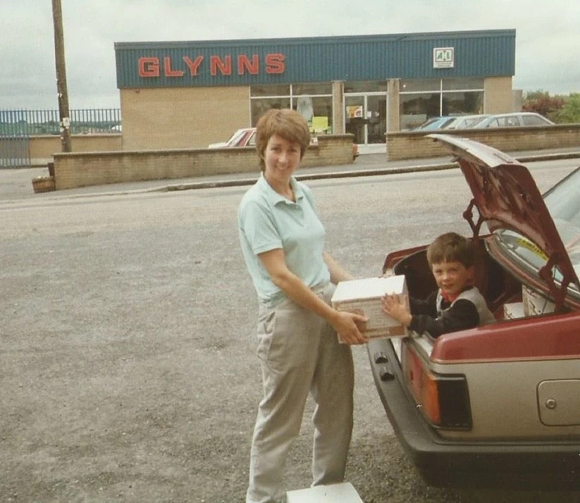 Margaret (aka our mother) passing Matt a box of Coffee before Bryan heads off for his daily deliveries, 1990